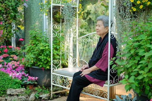 old elder woman resting in flower garden. asian elderly female relaxing in park. senior leisure lifestyle