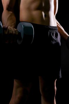 portrait of athletic muscular bodybuilder man with naked torso six pack abs working out with dumbbell. fitness sport exercise concept