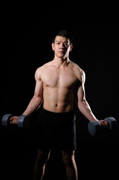 portrait of athletic muscular bodybuilder man with naked torso six pack abs working out with dumbbell. fitness sport exercise concept