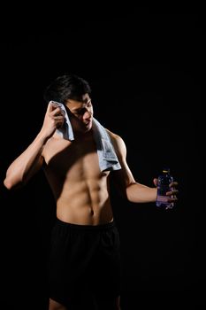 portrait of athletic muscular bodybuilder man with naked torso six pack abs holding water bottle. fitness workout concept