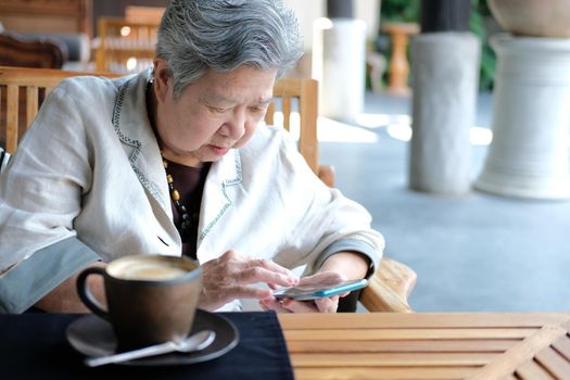 asian elder senior woman using mobile smart phone. elderly female holding cellphone. mature retirement lifestyle