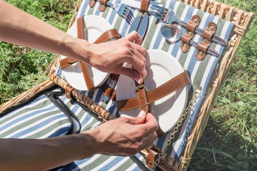 Young woman hands unpacking picnic basket outdoors, ready to have a picnic