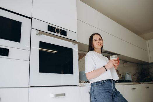 Bake in the oven. Smiling young girl in an apron crouched near the oven and opened the door, looking joyful