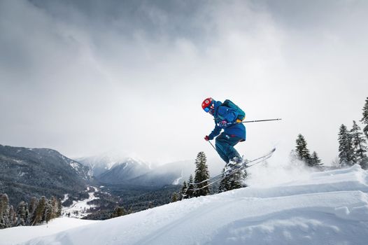 Freeride, a man is stylishly skiing on a snowy slope with snow dust plume behind him.