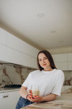 Beautiful young woman drinking coffee in kitchen.