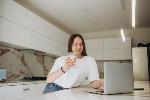 Happy woman using laptop in cook room.