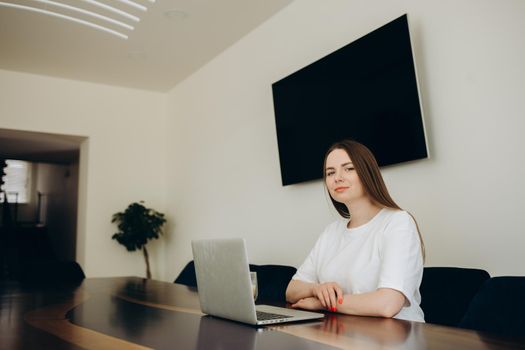 Young woman using laptop near TV in room.