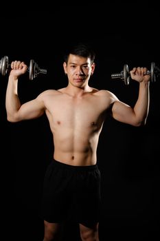 portrait of athletic muscular bodybuilder man with naked torso six pack abs working out with dumbbell. fitness sport exercise concept