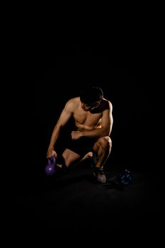 portrait of athletic muscular bodybuilder man with naked torso six pack abs working out with kettle bell. fitness sport exercise concept