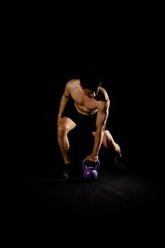 portrait of athletic muscular bodybuilder man with naked torso six pack abs working out with kettle bell. fitness sport exercise concept