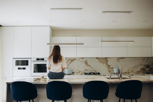 young woman sitting at the kitchen table with her back to the camera. rear view