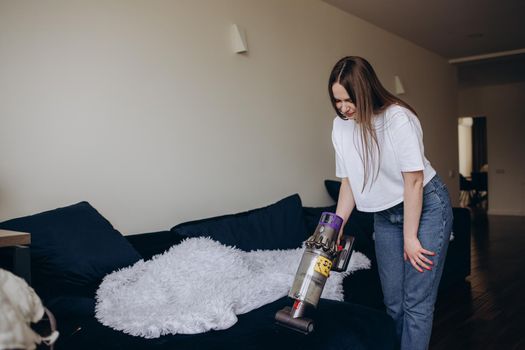 Young woman with rechargeable vacuum cleaner cleaning at home.