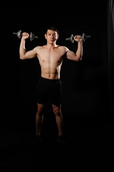 portrait of athletic muscular bodybuilder man with naked torso six pack abs working out with dumbbell. fitness sport exercise concept