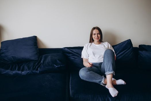 Young woman changing channels with remote control.