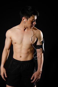 portrait of athletic muscular bodybuilder man with smart mobile phone armband listening to music. fitness workout concept