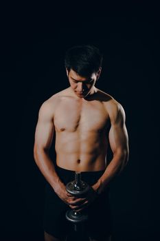 portrait of athletic muscular bodybuilder man with naked torso six pack abs working out with dumbbell. fitness sport exercise concept