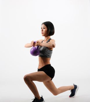 asian sporty woman in sportswear with kettlebell doing fitness workout on white background. healthy sport lifestyle