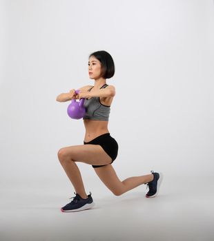 asian sporty woman in sportswear with kettlebell doing fitness workout on white background. healthy sport lifestyle