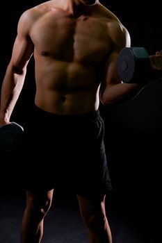 portrait of athletic muscular bodybuilder man with naked torso six pack abs working out with dumbbell. fitness sport exercise concept