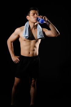 portrait of athletic muscular bodybuilder man with naked torso six pack abs drinking water. fitness workout concept