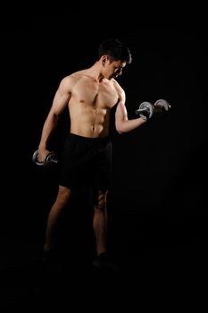 portrait of athletic muscular bodybuilder man with naked torso six pack abs working out with dumbbell. fitness sport exercise concept