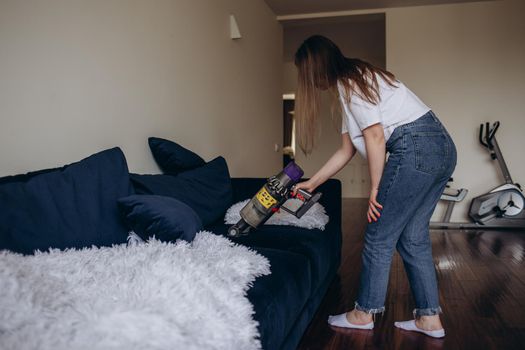 girl cleaning the sofa with a vacuum cleaner.