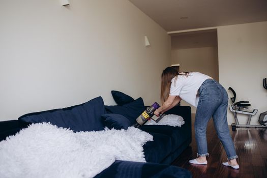 Young woman with rechargeable vacuum cleaner cleaning at home.