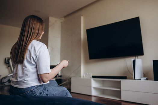 Young woman watching TV in the room.