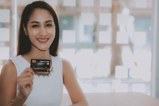 smiling asian woman with credit card for shopping online.