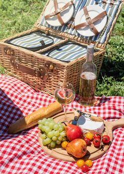 Closeup of picnic basket with drinks and food on the grass. Nice picnic on sunny summer day, fun and leisure