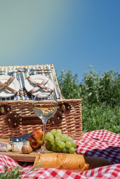 Closeup of picnic basket with drinks and food on the grass. Nice picnic on sunny summer day, fun and leisure