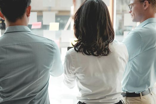 business people working planning discussing idea with sticky reminder note on glass wall at workplace