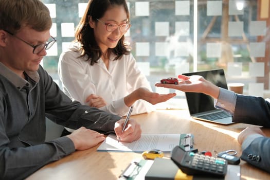 dealer salesman giving car to new owner. client signing insurance document or rental car lease form