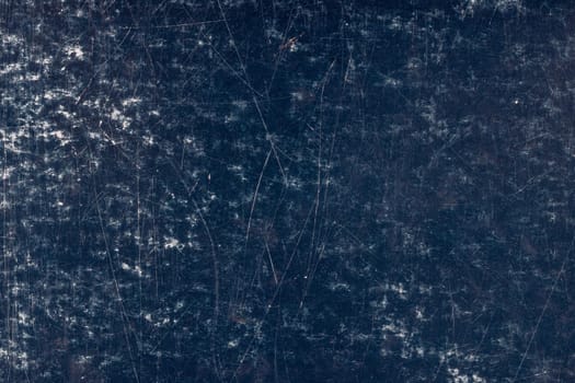 Heavily scratched dark blue surface of painted cardboard, flat full-frame background and texture