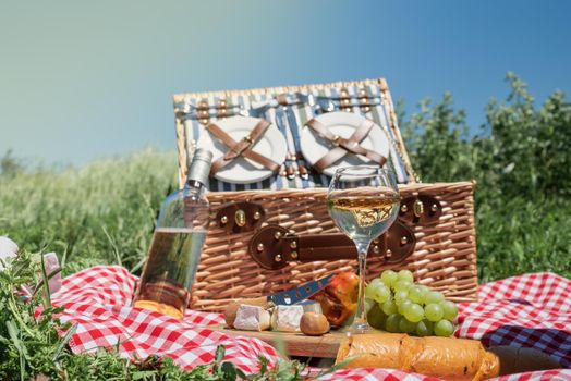 Closeup of picnic basket with drinks and food on the grass. Nice picnic on sunny summer day, fun and leisure