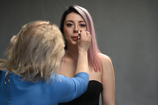 Make-up artist corrects the model's makeup in front of the face