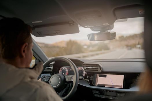 Rear of man driver driving car, shot from inside the car, people traveling in vehicle. Trip concept