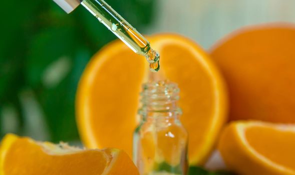 Orange essential oil in a small bottle. Selective focus. Nature.