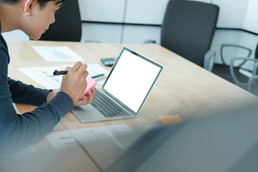 startup man writing reminder on sticky note. male freelancer student working organizing plan at workplace