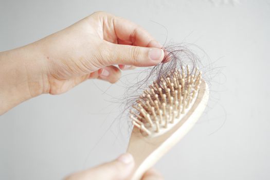young women hold his list hair against white wall .