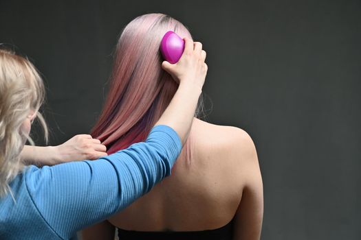 Hairdresser combing model's hair from behind