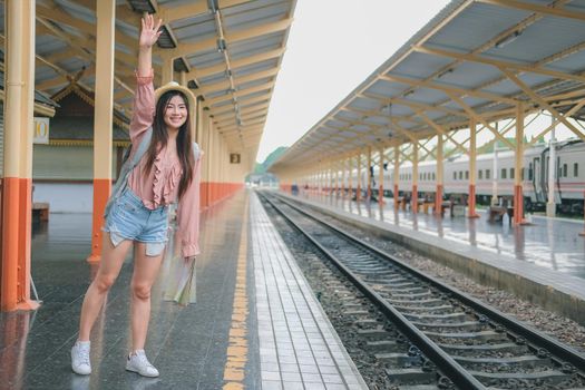 woman traveler with backpack map raising waving hand at train station. trip journey travel concept