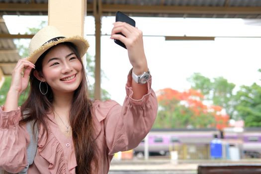 asian woman use smart phone to take selfie photo at train station. traveler travel on holiday