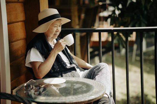 old elderly senior elder woman drinking hot coffee on terrace. mature retirement lifestyle