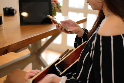 woman playing guitar using mobile smart phone at home