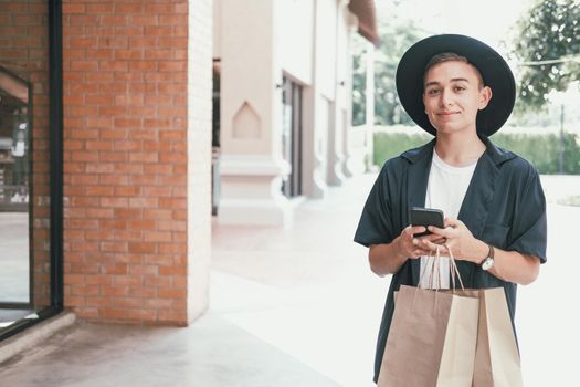 man holding paper shopping bags & using mobile smart phone. consumerism lifestyle