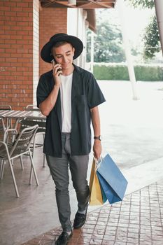 man holding paper shopping bags & talking on mobile smart phone. consumerism lifestyle