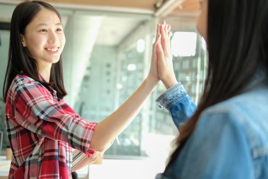 girl teenager giving high five touching hands together. teamwork friendship amity concept