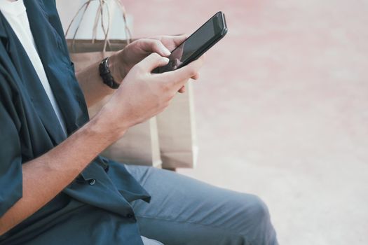 man using mobile smart phone with paper shopping bags. consumerism lifestyle