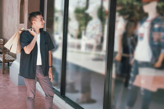 man holding shopping bags looking at shop store window